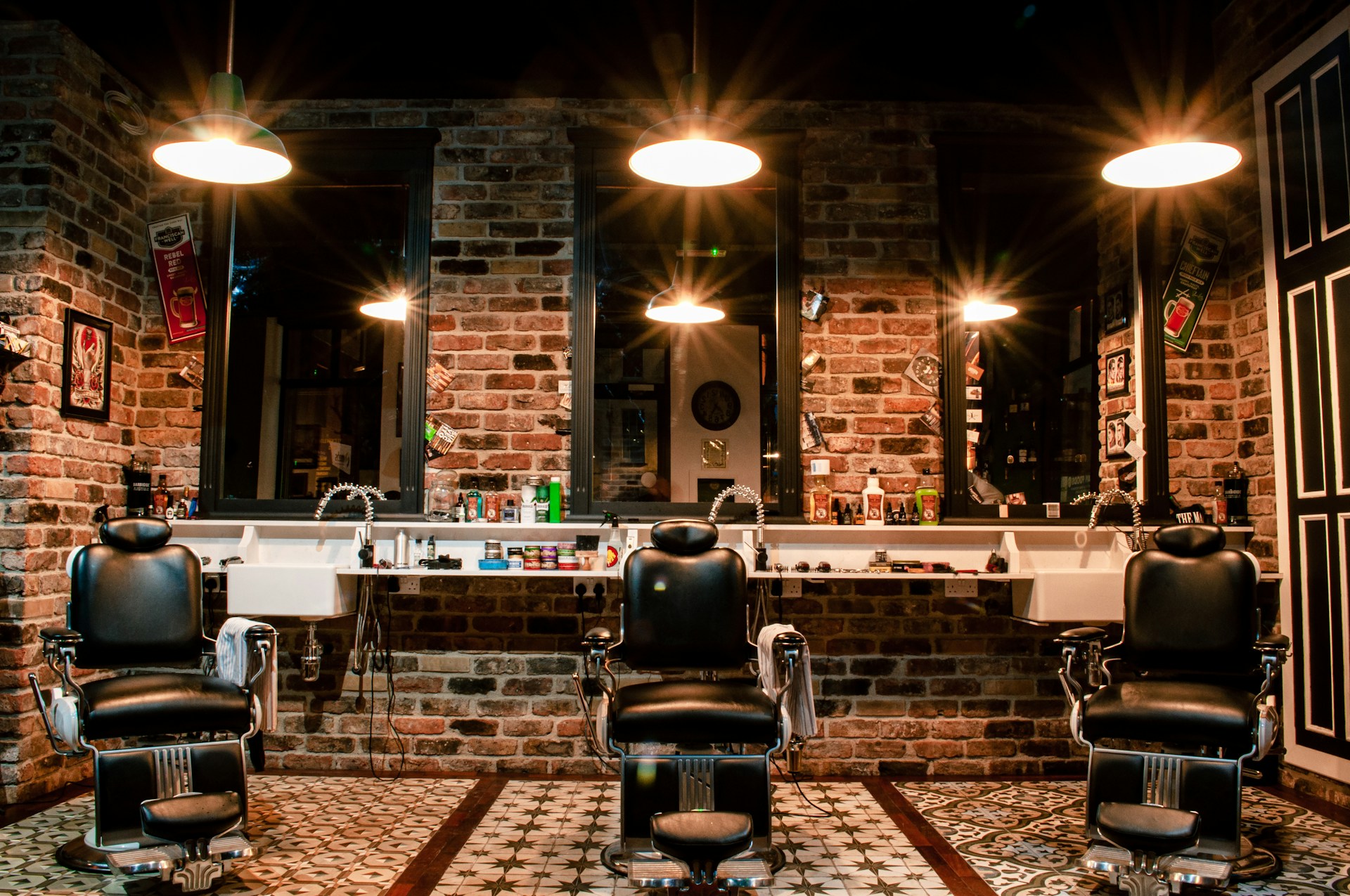 Barbershop interior with exposed brick walls and three vintage barber chairs