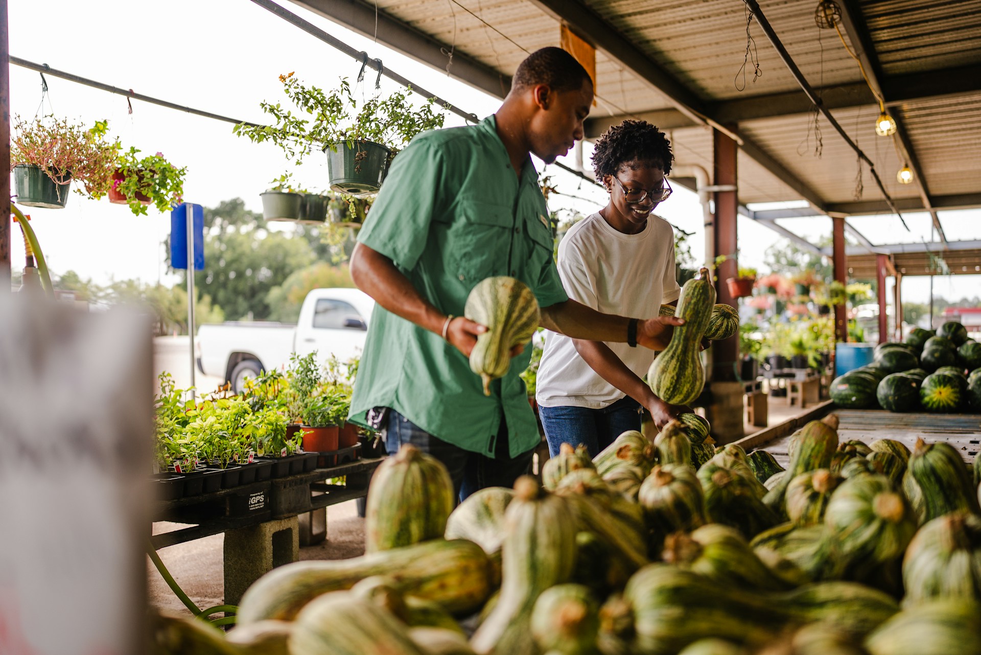 Couple selecting squash at an open-air farmers market stand